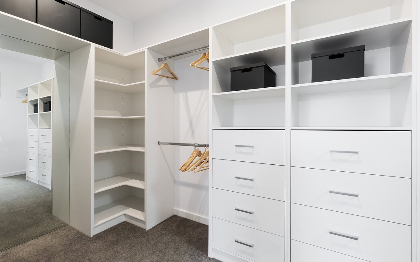 Large walk in wardrobe with custom built cabinetry, a full length mirror and drawers